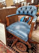 A BLUE UPHOLSTERED DESK CHAIR ROTATING ON FOUR CRUCIFORM LEGS WITH CASTER FEET
