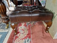 A STOOL BUTTON UPHOLSTERED IN BROWN AND ON MAHOGANY CABRIOLE LEGS WITH PAD FEET