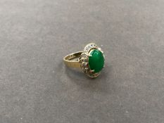 A JADE AND DIAMOND CLUSTER RING. THE JADE CABOCHON MEASURING 12.2 X 9.8 X D 2.9mm, APPROXIMATE