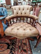 A BUTTON UPHOLSTERED PALE BROWN LEATHER DESK CHAIR ROTATING ON FOUR CROSS FORM LEGS WITH CASTER