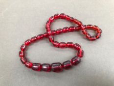 A STRING OF VINTAGE RED CYLINDRICAL GRADUATED BEADS.