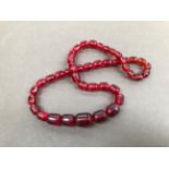 A STRING OF VINTAGE RED CYLINDRICAL GRADUATED BEADS.