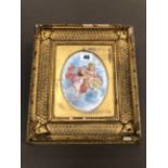 AN ANTIQUE GILT FRAMED HAND PAINTED PORCELAIN PLAQUE DECORATED WITH CHERUBS.