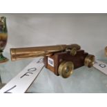 A BRONZE MODEL CANNON ON A WOODEN CARRIAGE WITH BRASS WHEELS