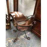 A CHRISTOPHER DRESSER STYLE COPPER COAL SCUTTLE CRADLED IN AN IRON STAND ON FOUR SCROLL LEGS