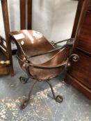 A CHRISTOPHER DRESSER STYLE COPPER COAL SCUTTLE CRADLED IN AN IRON STAND ON FOUR SCROLL LEGS