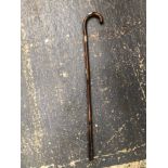 AN ANTIQUE WALKING STICK WITH SILVER MOUNTS AND A CONCEALED PENCIL.