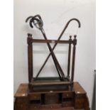 A MAHOGANY STICK STAND WITH THREE WALKING STICKS AND A SHOOTING STICK TOGETHER WITH A WROUGHT IRON