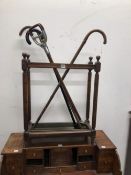 A MAHOGANY STICK STAND WITH THREE WALKING STICKS AND A SHOOTING STICK TOGETHER WITH A WROUGHT IRON