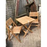 A GOOD QUALITY TEAK PATIO TABLE AND TWO MATCHING CHAIRS