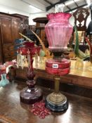 A VICTORIAN CRANBERRY GLASS OIL LAMP AND SHADE AND A SIMILAR CUT GLASSED LUSTER