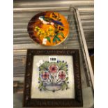 A CIRCULAR TILE DECORATED WITH A BIRD EATING FRUIT TOGETHER WITH A FRAMED FLORAL TILE