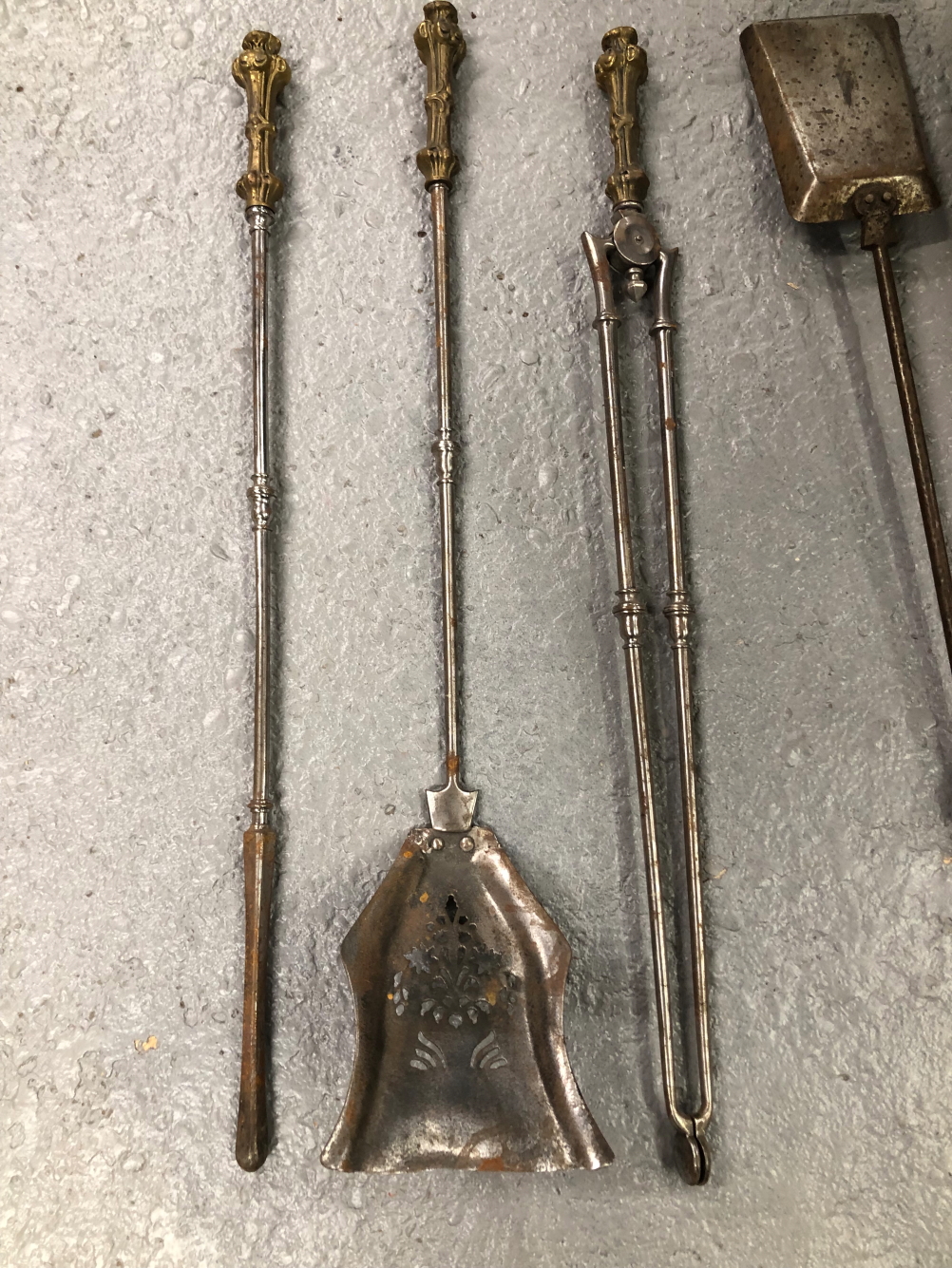 A SET OF THREE POLISHED STEEL FIRE IRONS WITH NEOGOTHIC BRASS HANDLES TOGETHER WITH ANOTHER SET OF