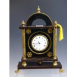 A TIMEPIECE IN A BRASS MOUNTED EBONISED WOODEN CASE, THE ENAMEL DIAL FLANKED BY COLUMNS. H 28cms.