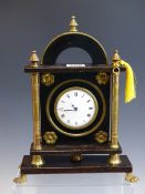 A TIMEPIECE IN A BRASS MOUNTED EBONISED WOODEN CASE, THE ENAMEL DIAL FLANKED BY COLUMNS. H 28cms.