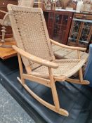 A RETRO MID CENTURY ROPE BACK ROCKING CHAIR IN THE MANNER OF HANS WEGNER