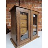 AN EARLY 20th C. LINE INLAID OAK SMOKING COMPENDIUM WITH GLAZED DOORS OVER THREE DRAWERS AND A