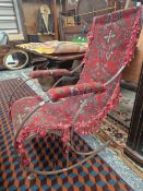 A ANTIQUE WROUGHT IRON ROCKING CHAIR WITH CARPET SLUNG UPHOLSTERY