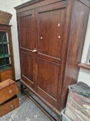 A LARGE ANTIQUE OAK HALL CABINET WITH SHELVED INTERIOR RAISED ON A TURNED LEGGED STAND