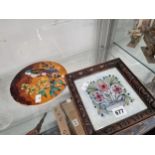 A CIRCULAR TILE SLIP DECORATED WITH A BIRD AND FLOWERS TOGETHER WITH A FRAMED FLORAL TILE