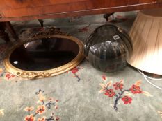A LARGE GLASS LAMP AND AN OVAL GILT FRAMED WALL MIRROR