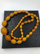 A GRADUATED CONTINUOUS ROW OF OVAL AMBER BEADS INTERSPERSED WIT FACET CUT ROUNDLES. LENGTH 84cms.