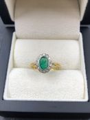 AN ANTIQUE 18ct AND PLATINUM STAMPED EMERALD AND DIAMOND OVAL CLUSTER RING. HEAD MEASUREMENTS 11.2 X