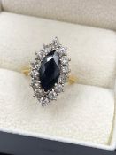 AN 18ct HALLMARKED GOLD MARQUISE CUT BLUE SAPPHIRE AND DIAMOND CLUSTER RING. THE SAPPHIRE
