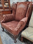 A LARGE WINGBACK ARMCHAIR WITH CARVED LOWER FRAME AND LEGS.