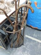 AN EDWARDIAN BRASS AND IRON STICK STAND CONTAINING A HORSE MEASURE WALKING STICK AND FOUR OTHERS.