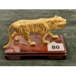 A GILDED ORIENTAL FIGURE OF A TIGER ON HARDWOOD BASE.