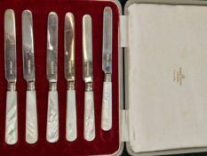 A CASED SET OF HALLMARKED SILVER BLADED BUTTER KNIVES WITH MOTHER OF PEARL HANDLES.