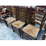 THREE RUSH SEAT LADDER BACK CHAIRS AND A SPINDLE BACK ARM CHAIR.