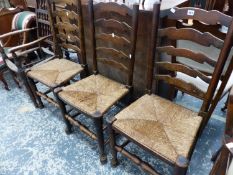 THREE RUSH SEAT LADDER BACK CHAIRS AND A SPINDLE BACK ARM CHAIR.