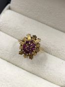 A 9ct HALLMARKED GOLD RUBY CLUSTER AND STAR BURST RING. FINGER SIZE J. WEIGHT 2.37grms.
