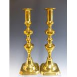 A PAIR OF LARGE VICTORIAN BRASS CANDLESTICKS WITH CENTRAL PUSHERS.
