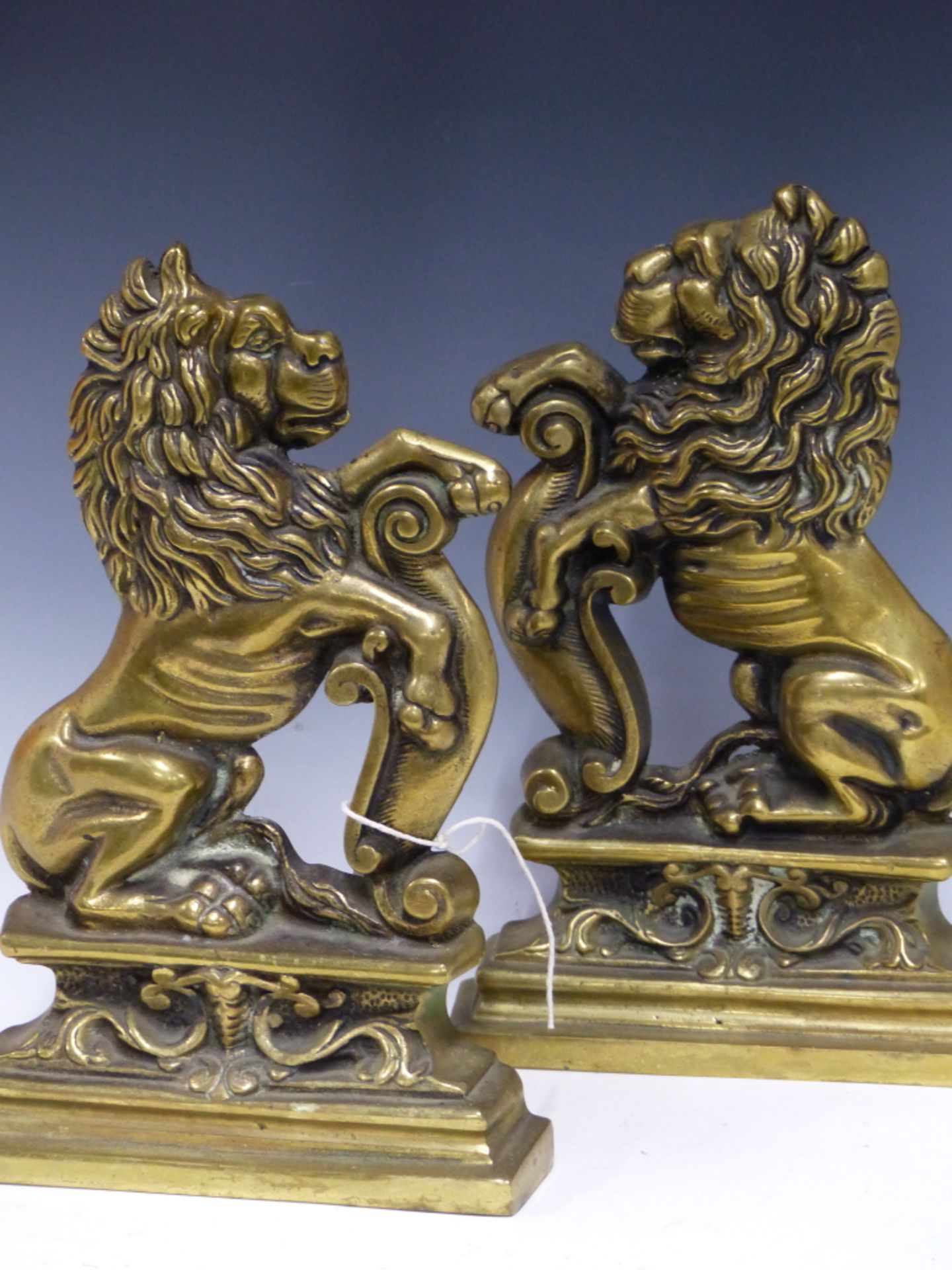 A PAIR OF ANTIQUE CAST BRASS RAMPANT LION FIRESIDE STANDS OR DOORSTOPS.