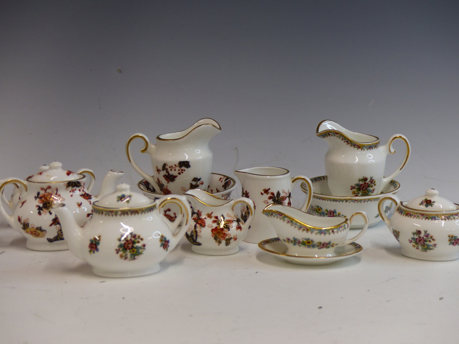 A COALPORT HONG KONG PATTERN MINIATURE TEA SERVICE AND A COALPORT MING ROSE MINIATURE TEA SERVICE.