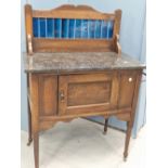 AN EARLY 20th CENTURY ARTS AND CRAFTS STYLE OAK MARBLE TOPPED WASHSTAND WITH BLUE GLAZED TILE BACK.