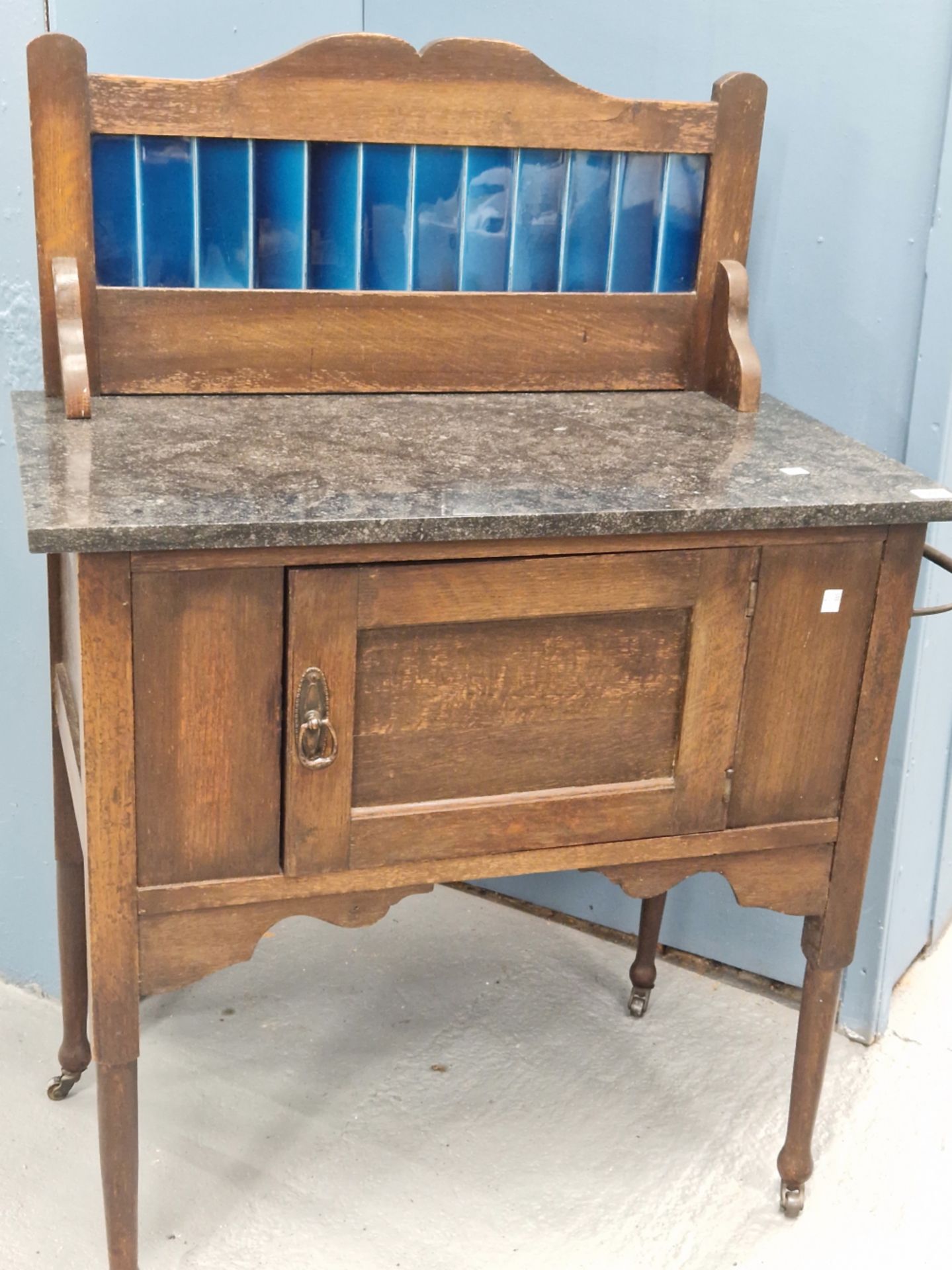 AN EARLY 20th CENTURY ARTS AND CRAFTS STYLE OAK MARBLE TOPPED WASHSTAND WITH BLUE GLAZED TILE BACK.