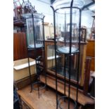 A PAIR OF GLASS AND IRON HURRICANE LANTERNS ON STANDS.