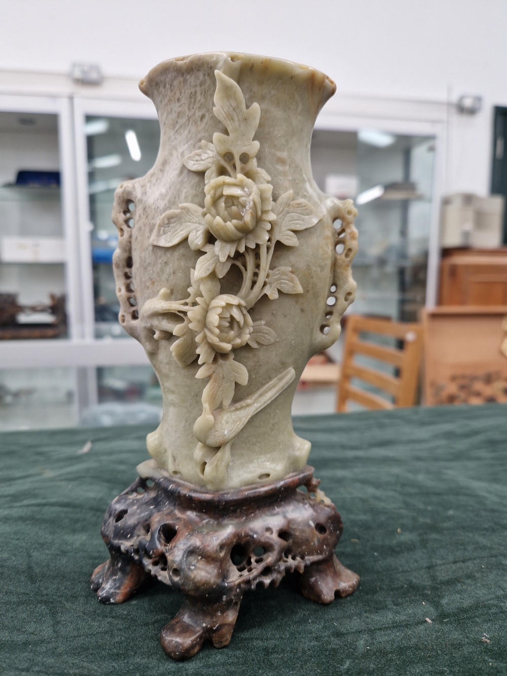 A CHINESE CELADON GREEN CARVED JADE SOAPSTONE VASE ON AN OPENWORK STAND WITH FOLIATE, FLORAL AND BIR