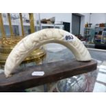 A CARVED BOARS TUSK ON STAND.