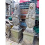 A PAIR OF COMPOSITE SEATED LIONS HOLDING SHIELDS ON PLINTH BASES.