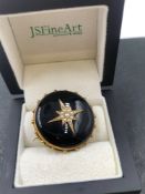AN ANTIQUE MOURNING BROOCH WITH GLAZED PANEL BACK AND A SEED PEARL STAR CENTRE. DIAMETER 3.2cms.