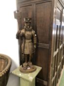 A PARCEL GILT IRON FIGURE OF A BEEFEATER SUPPORTING A SWORD POKER AND A FIRE BRUSH AT HIS BACK