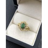 AN 18ct HALLMARKED GOLD EMERALD AND DIAMOND CLUSTER RING. THE OVAL EMERALD IN AN EIGHT CLAW