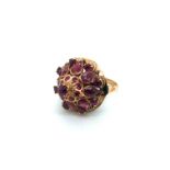 A CONTINENTAL RUBY DOMED CLUSTER RING. THE CLUSTER WITH PEAR AND ROUND CUT RUBIES. THE SHANK STAMPED