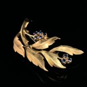AN 18ct HALLMARKED GOLD AND SAPPHIRE FLORAL BROOCH. MEASUREMENTS 4.0 X 2.0cms. WEIGHT 5.12grms.