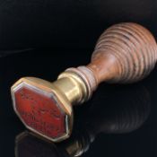 AN ANTIQUE CARNELAIN SEAL WITH BRASS MOUNT AND TURNED WOOD HANDLE. THE SEAL ENGRAVED WITH ARABIC